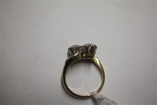 A gold and platinum, two stone diamond cross over ring, with diamond set shoulders, size O.